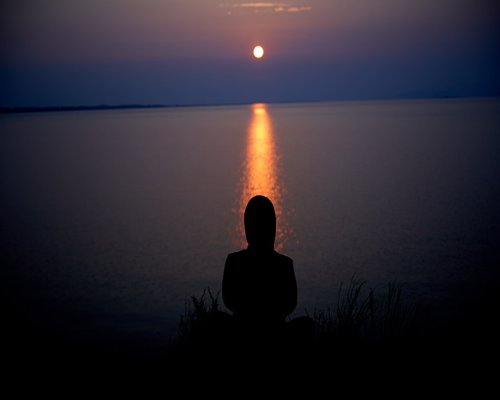 Calm person engaging in peaceful meditation at sunset